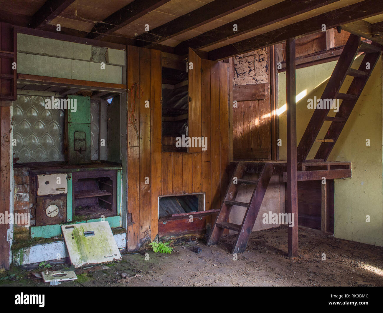 Broken wood stove and ladders to loft, interior of abandoned house, Ahu Ahu Ohu, Whanganui River, North Island, New Zealand Stock Photo