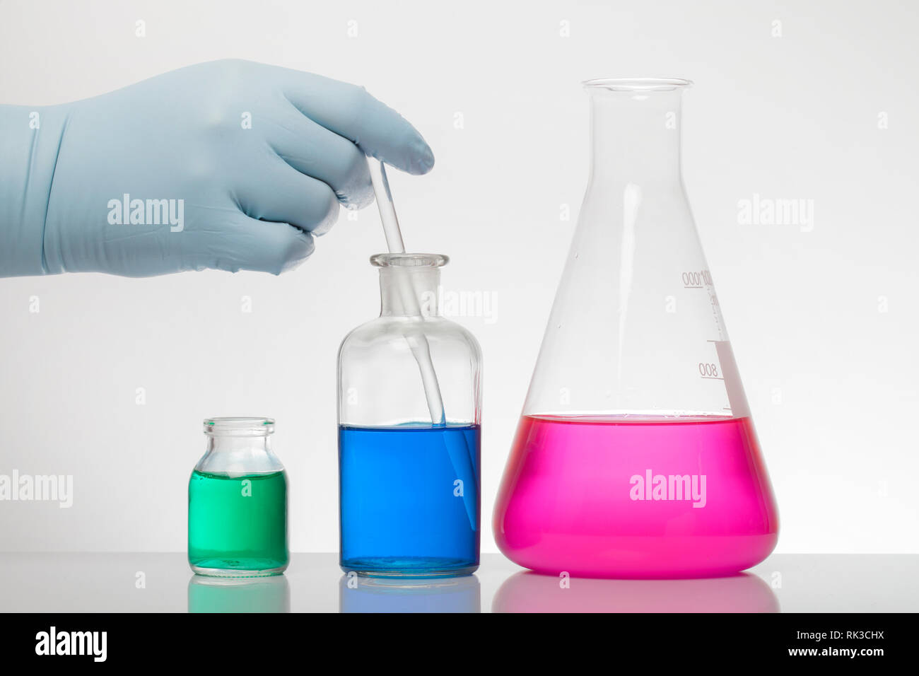 A hand in laboratory gloves mixes chemistry. Liquid in laboratory