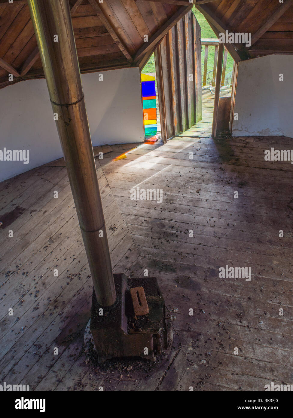 Wood stove chimney flue and open door to balcony, abandoned community building, Ahu Ahu Ohu, Whanganui River, New Zealand Stock Photo