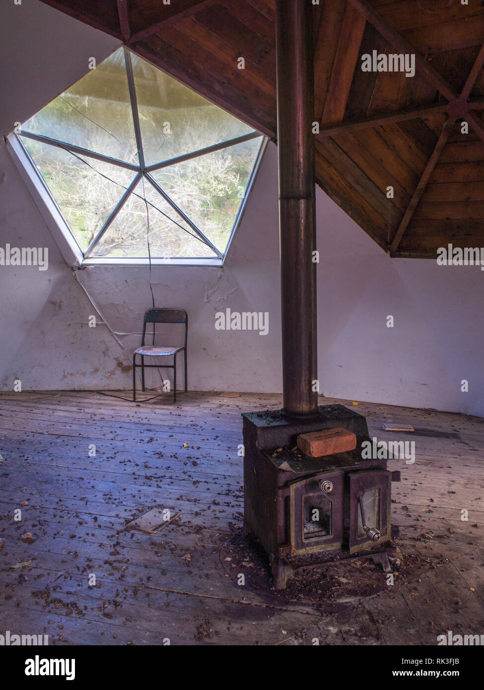 Empty chair and broken wood stove, interior of derelict community building, upstairs room, Ahu Ahu Ohu, Ahuahu Valley, Whanganui River, New Zealand Stock Photo