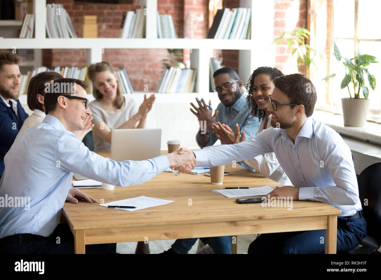 Happy partners shake hands get team applause after successful negotiations Stock Photo