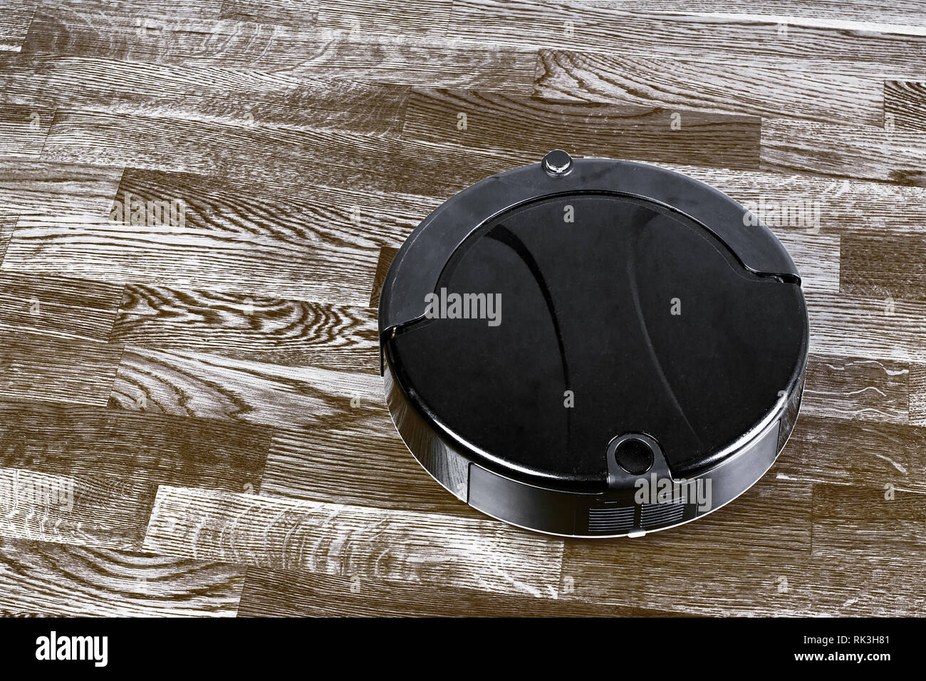 Robot vacuum cleaner runs on wood parquet floor. Modern smart cleaning ...