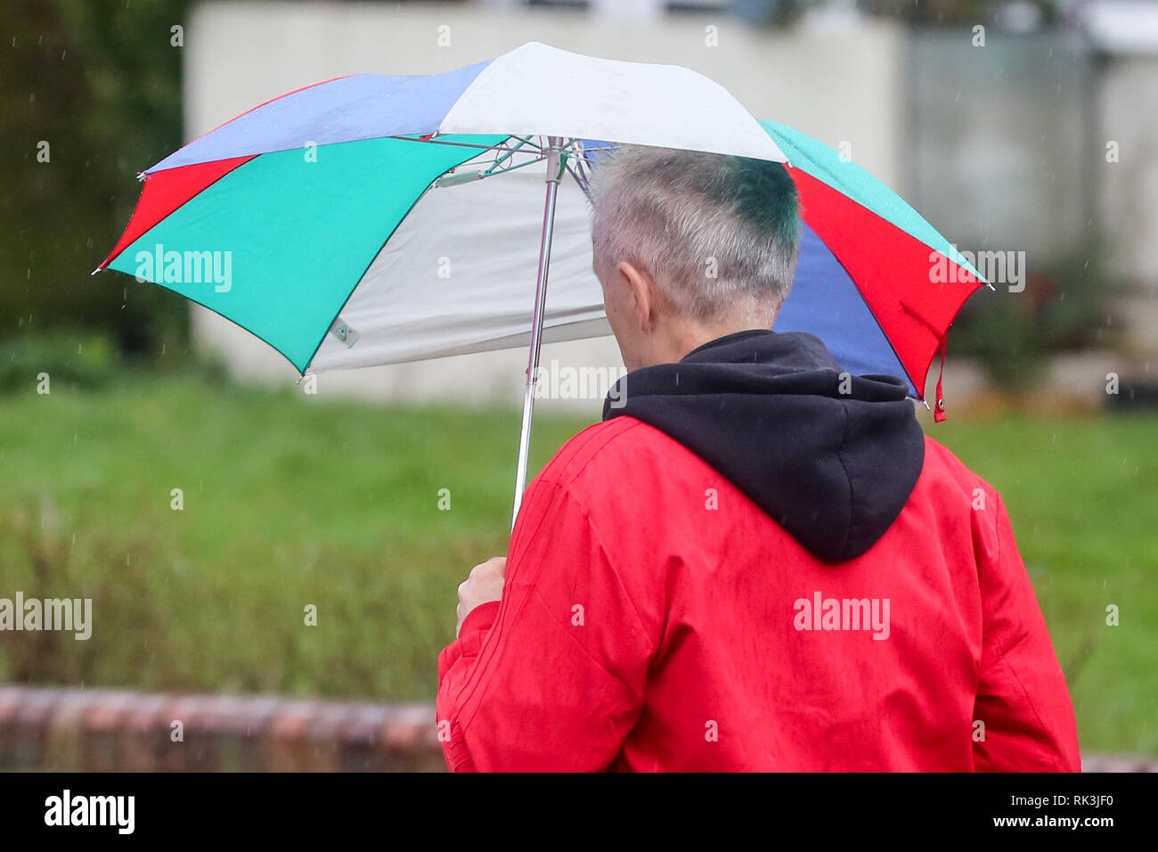 A man is seen sheltering from the rain under an umbrella during the strong winds and rain in the capital. Stock Photo