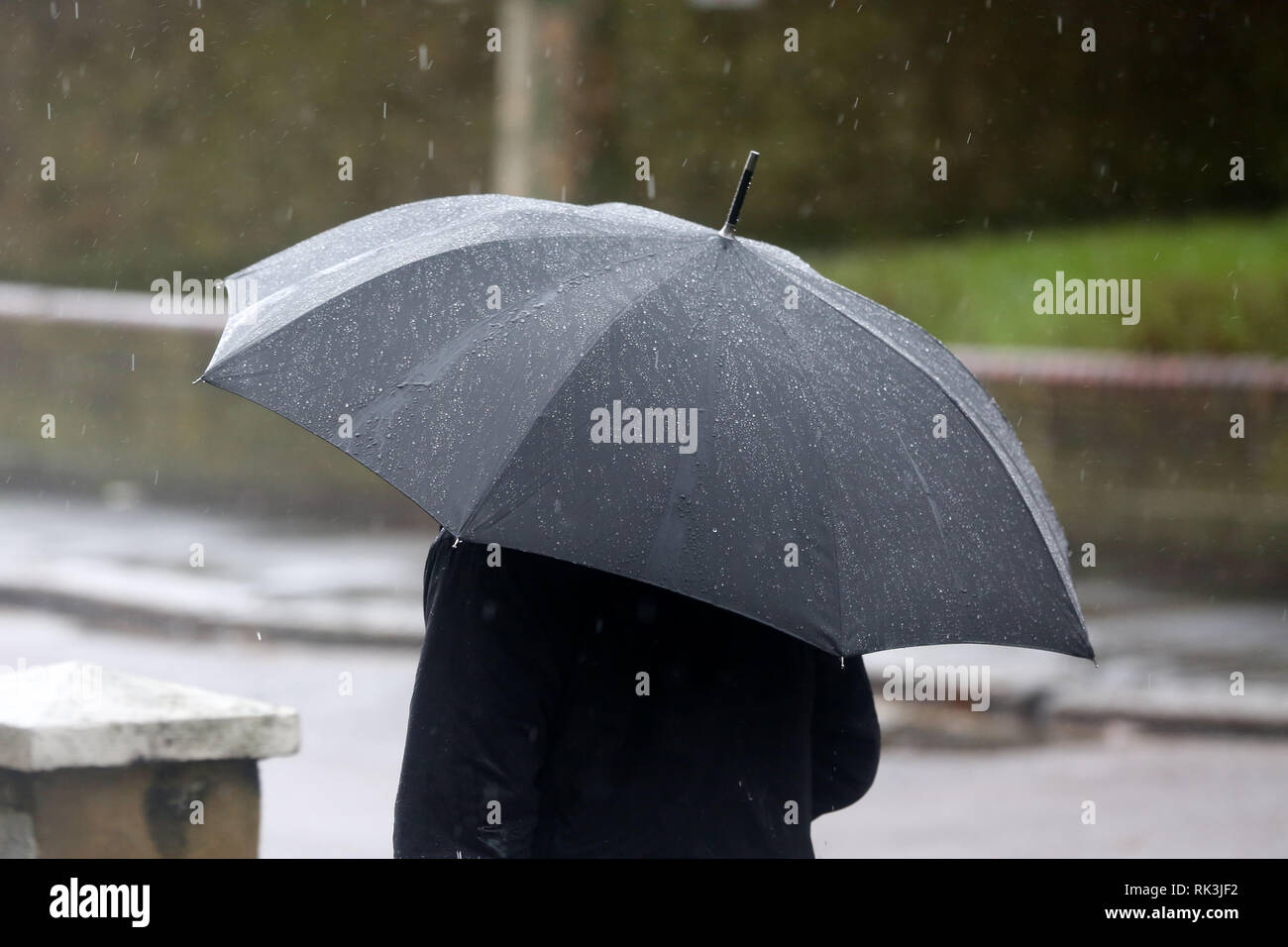 A man is seen sheltering from the rain under an umbrella during the strong winds and rain in the capital. Stock Photo