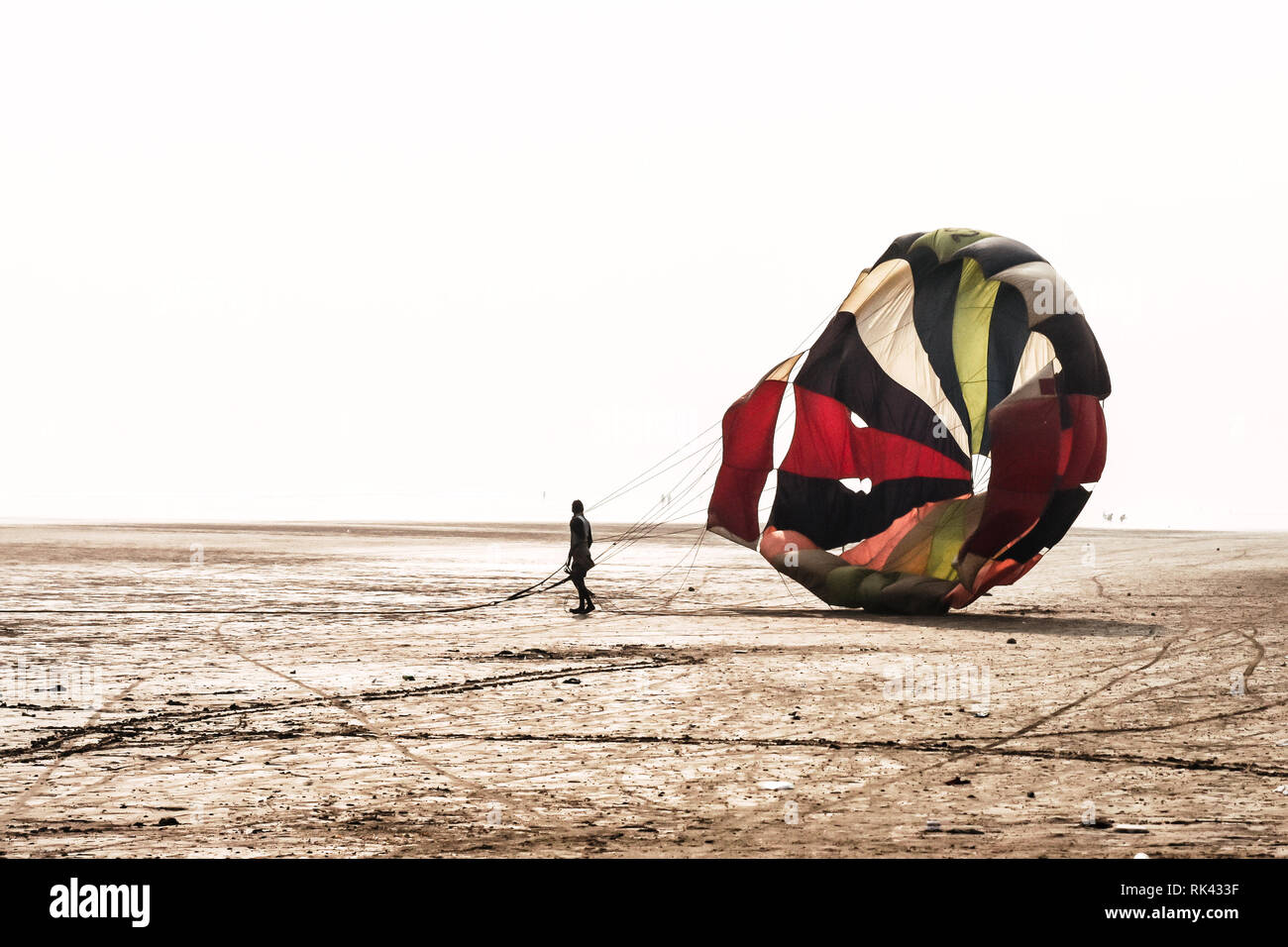 Man do some fold parachute after landing in a famous at Candolim Goa near Baga Beach and Vagator Beach. Yellow and blue wings slings are visible. Stock Photo