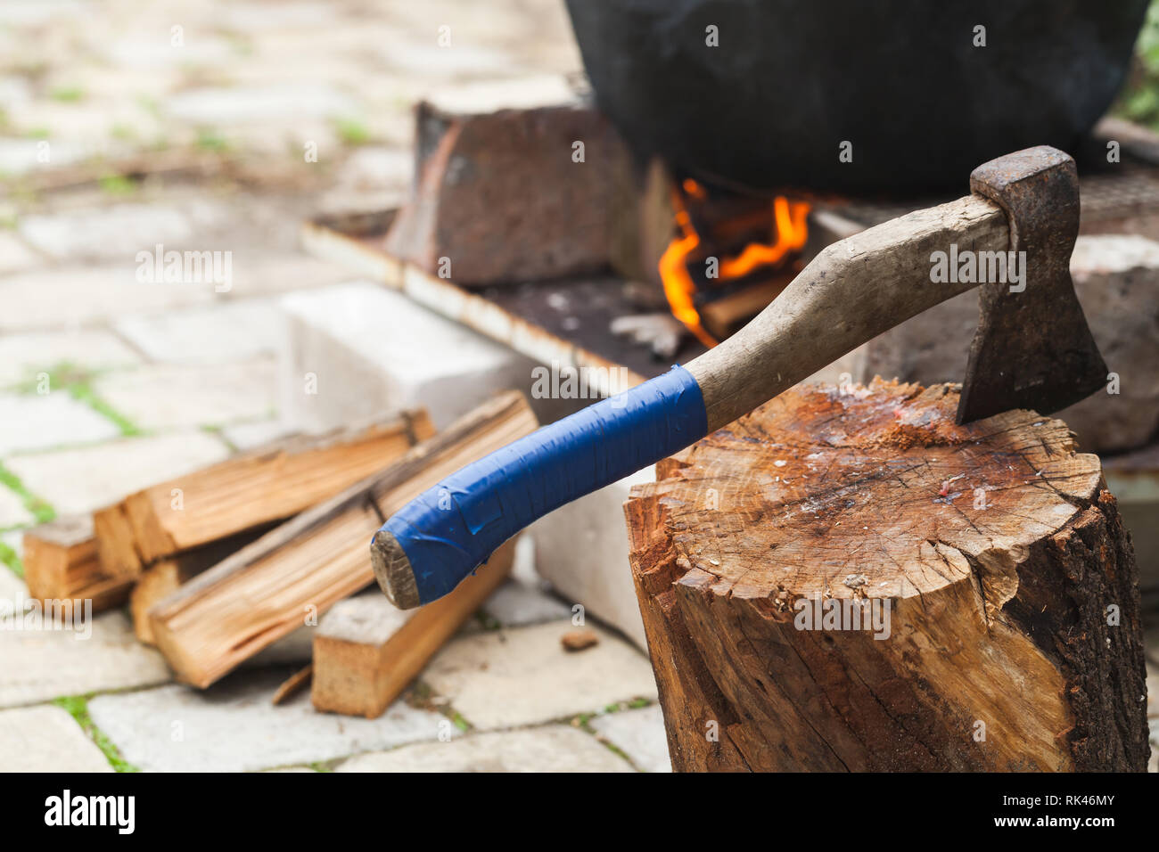 Ax stuck in a log near cauldron standing on a bonfire Stock Photo