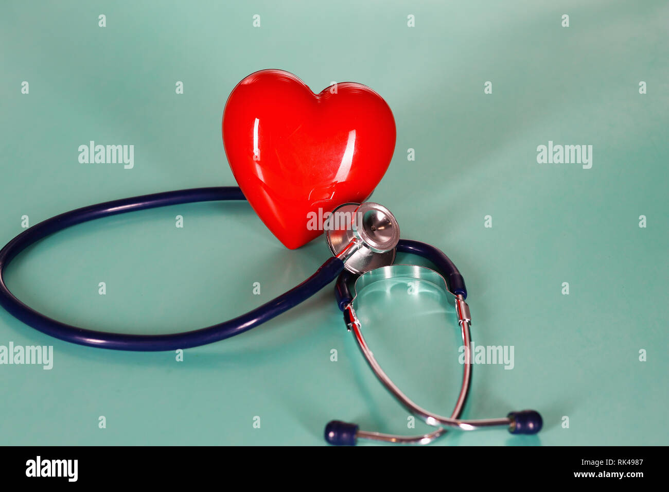 Red heart with stethoscope on blue wooden background Stock Photo - Alamy