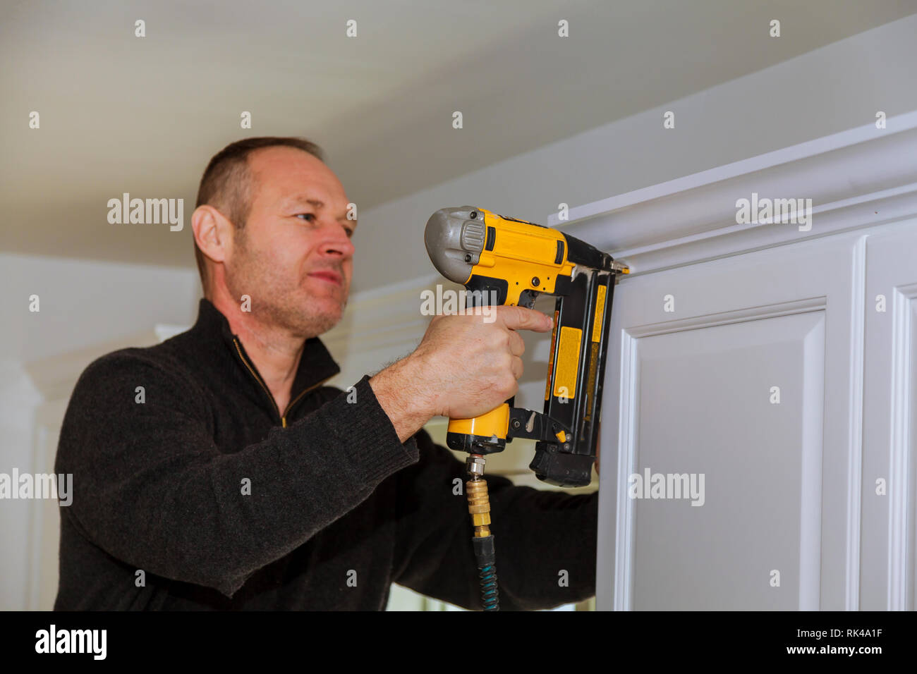 Air Nailer Tool, Carpenter using nail gun to crown moldings on kitchen