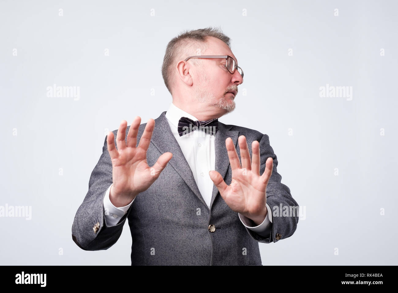 Senior male shows refusal gesture, does not want to participate in meeting Stock Photo