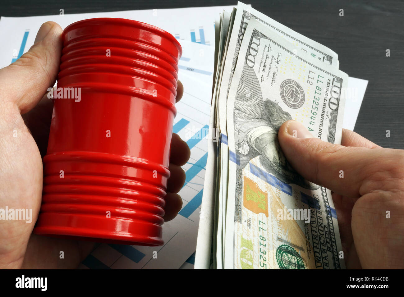 Hands are holding barrel and money. Oil trading. Stock Photo