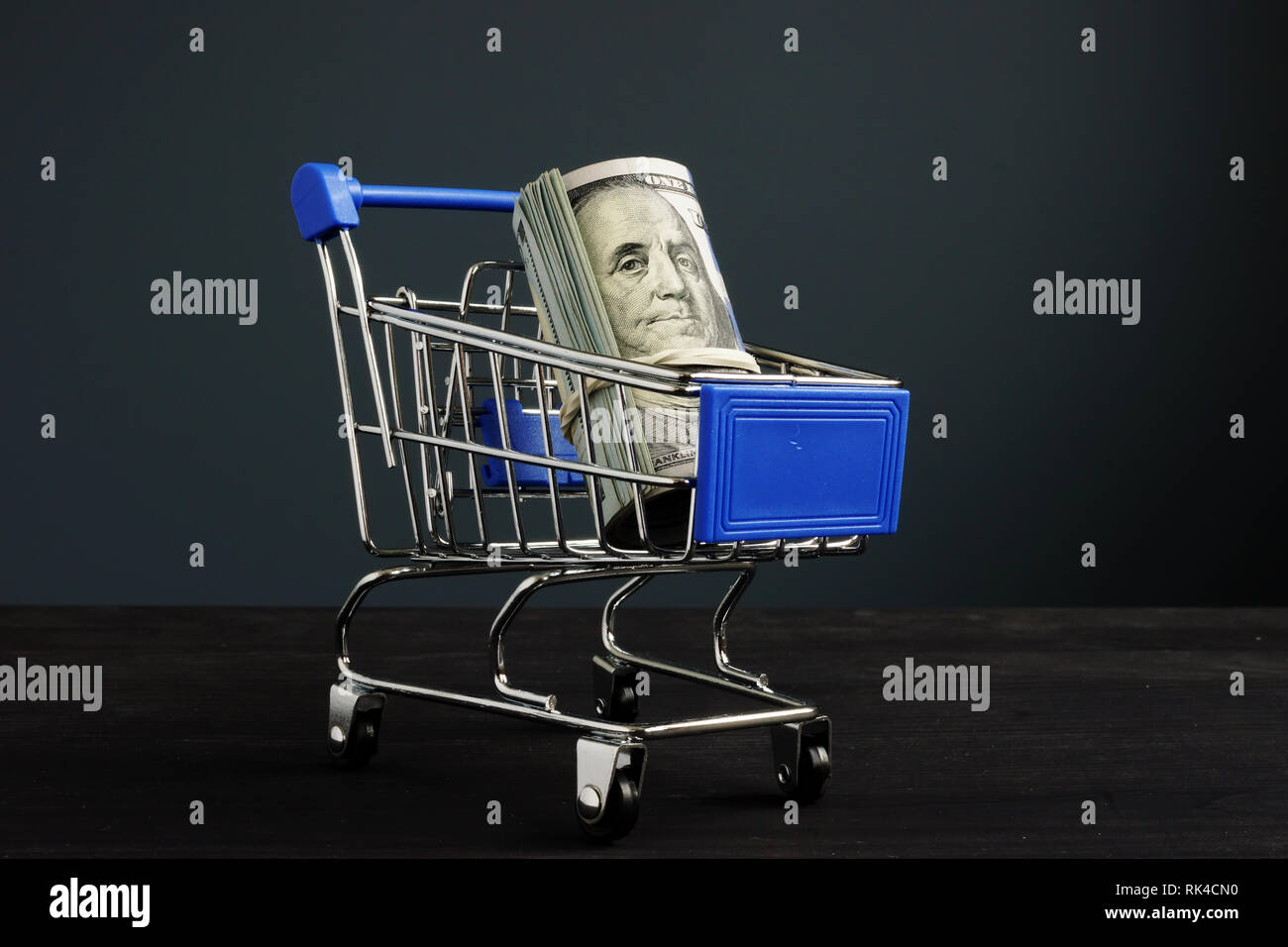 Shopping cart and roll of dollars. Money for loan and borrow cash. Stock Photo