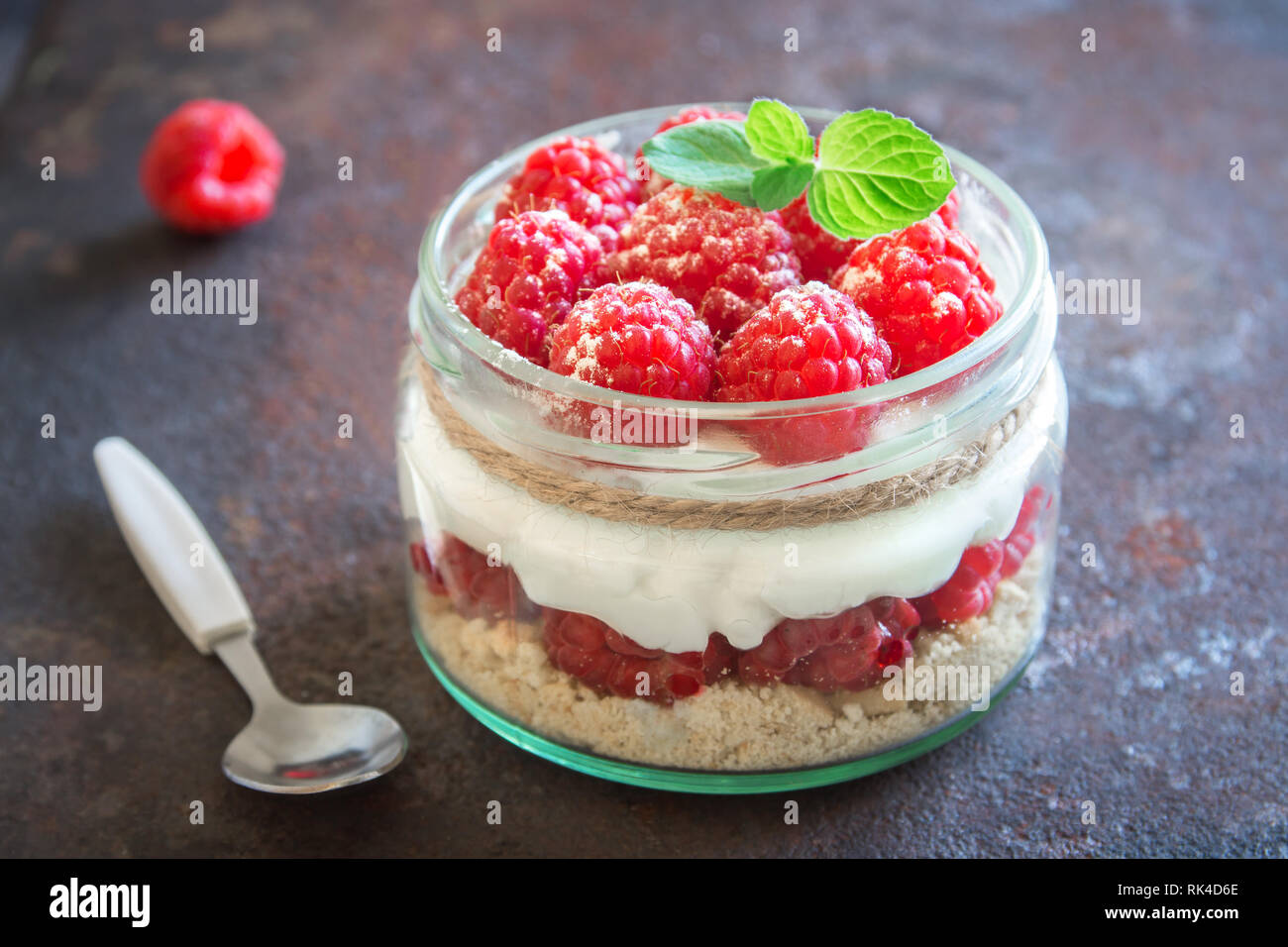 Raspberry layered dessert - cheesecake in glass jar with fresh raspberries and cream cheese. Healthy homemade summer berry dessert. Stock Photo