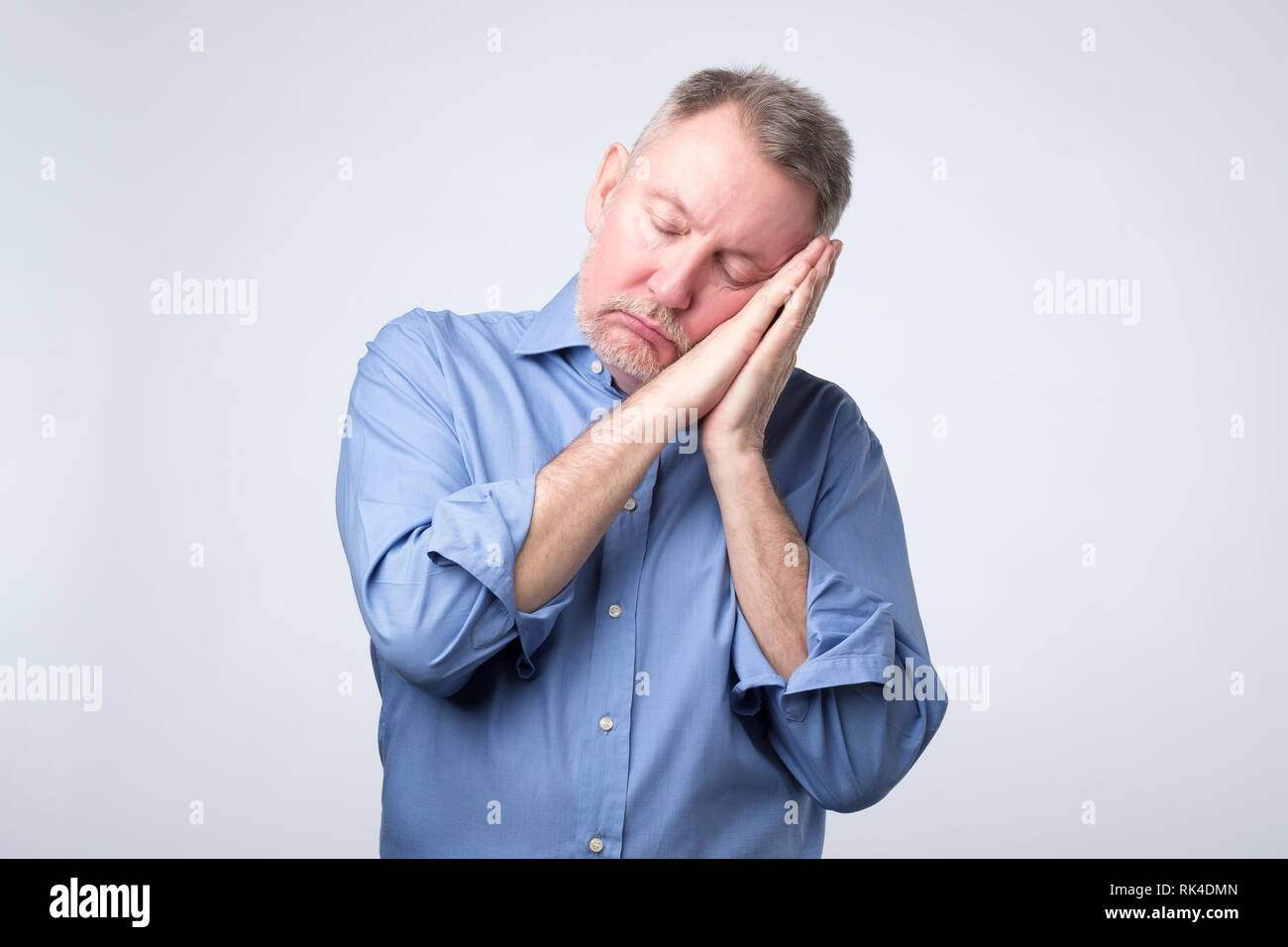 European man in blue shirt being tired sleeping on hands. Stock Photo