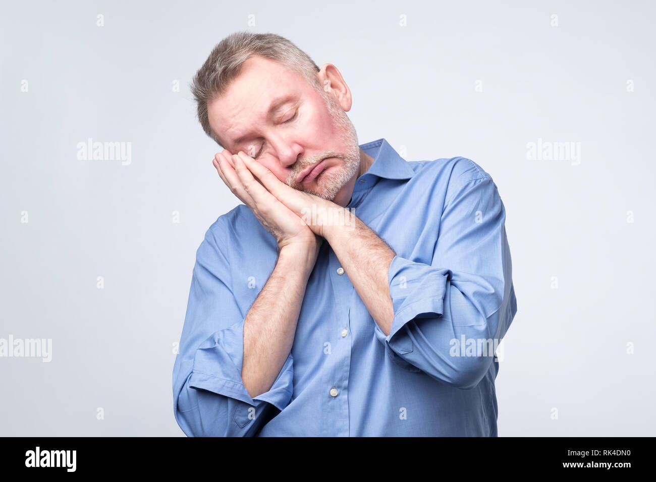 European man in blue shirt being tired sleeping on hands. Stock Photo
