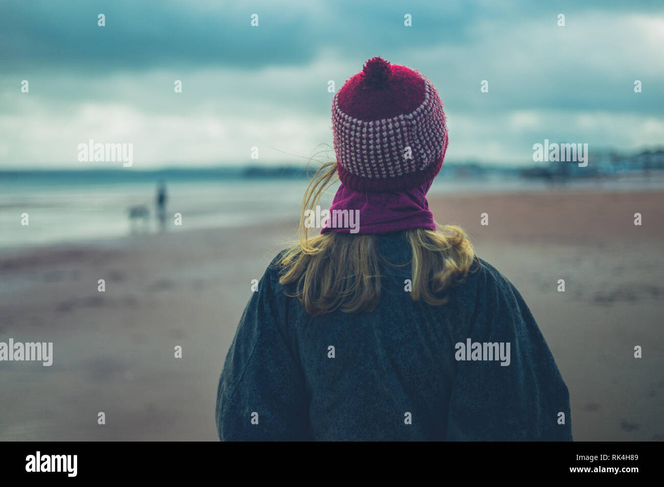 A young woman is walking on the beach in winter Stock Photo