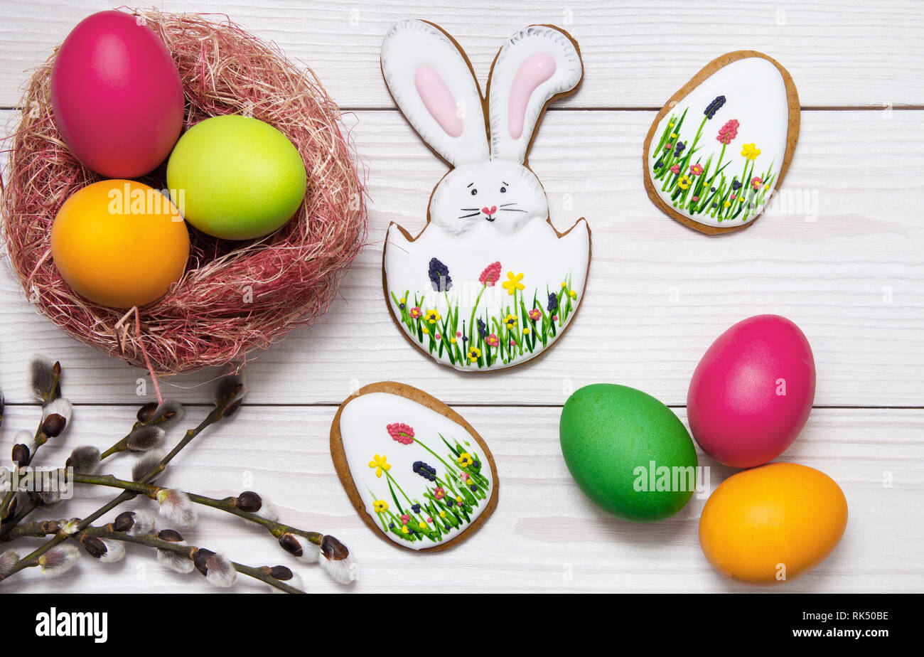Gingerbread Easter set painted eggs and willow twig on white wooden background. Easter Bunny and eggs, gingerbread Stock Photo