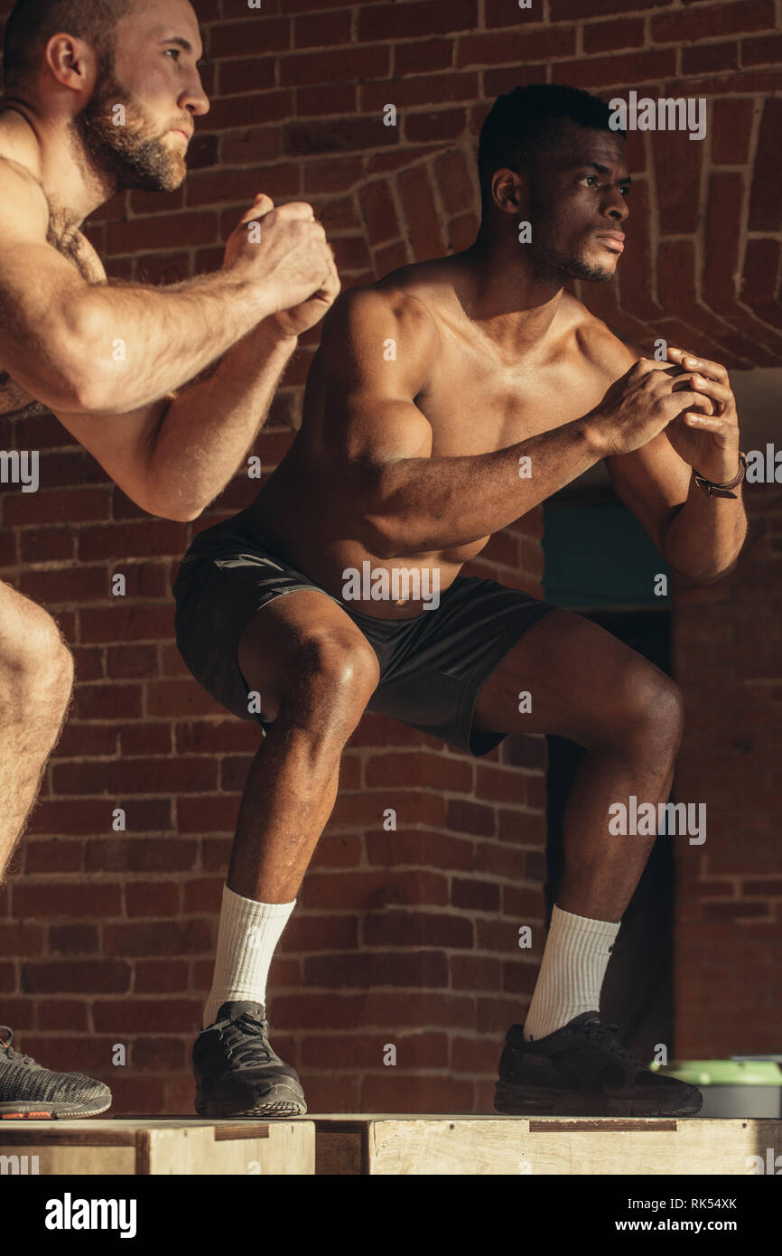 Jumping squats exercise with focus on body young caucasian and african athletes doing functional crossfit workout in fitness centre training physic Stock Photo Alamy