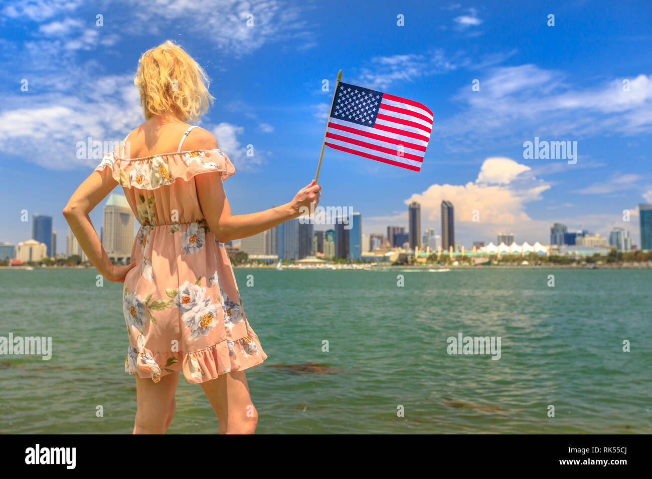 Tourism and travel in California, West Coast, USA. Blonde lady looking San Diego skyline with American flag waving from Coronado Island. Tourist woman Stock Photo