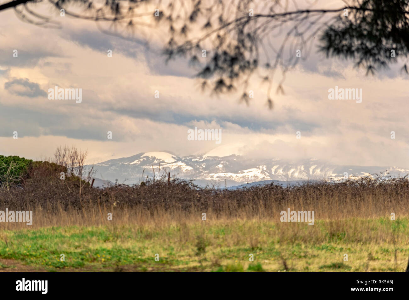 Seasonal  countryside landscape with snow mountains in the far background Stock Photo