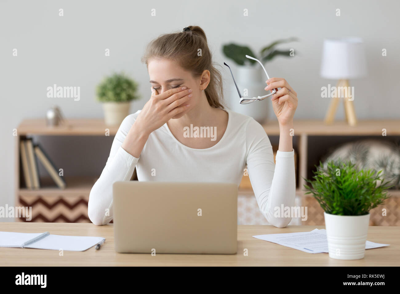 Tired woman rubbing eyes taking off glasses after computer work Stock Photo