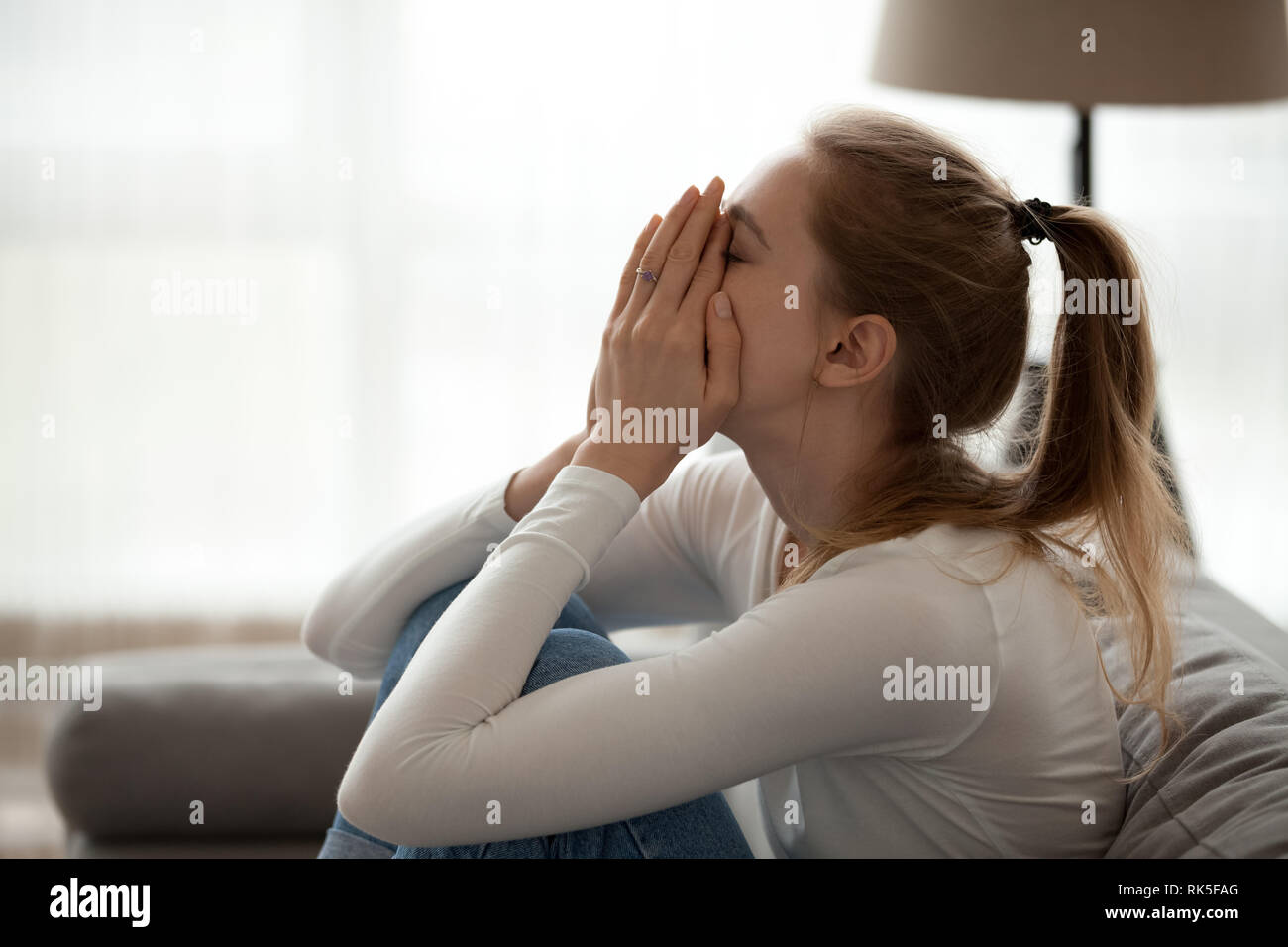 Depressed upset young woman crying alone at home Stock Photo