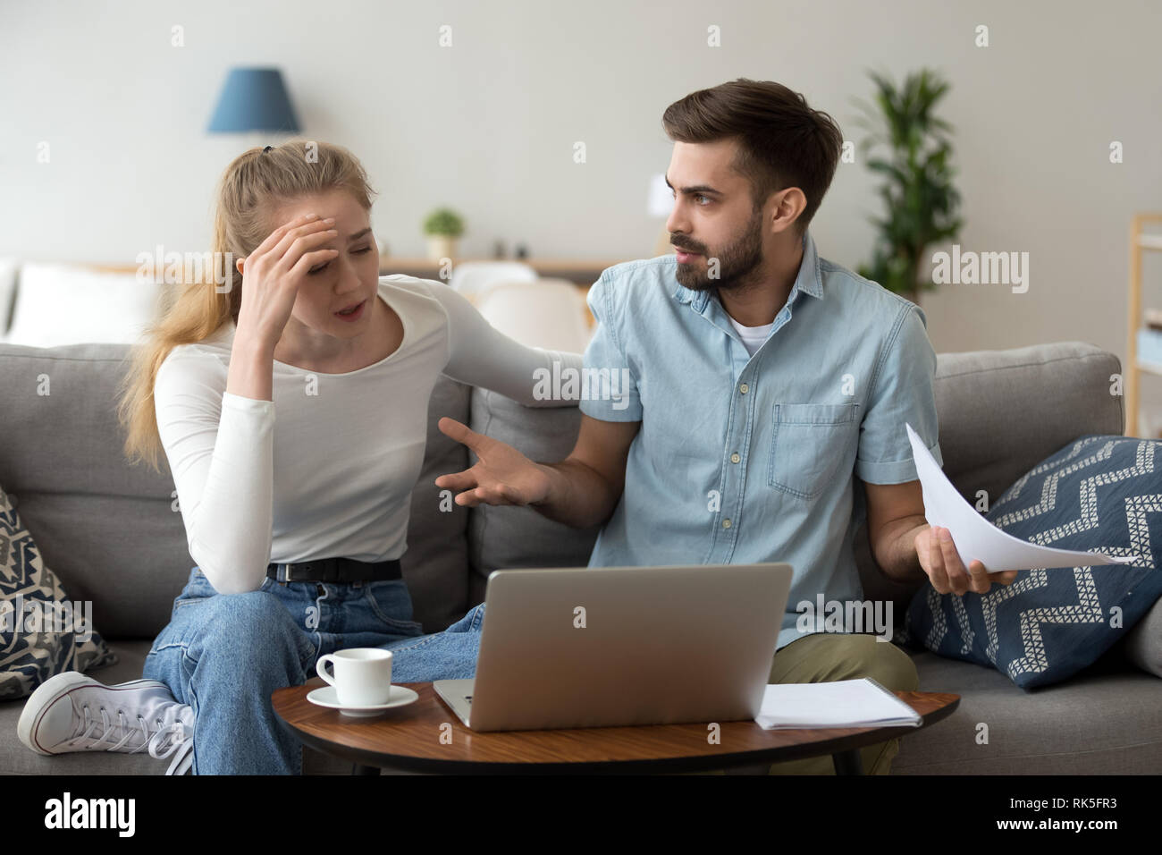 Stressed unhappy couple arguing about expenses with laptop and papers Stock Photo