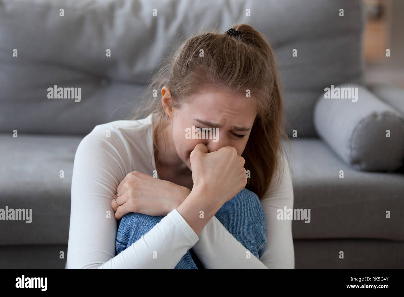 Desperate upset teen girl victim crying alone at home Stock Photo