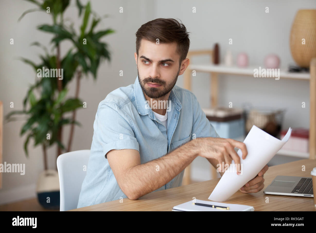 Serious thoughtful man holding papers thinking of problem solution Stock Photo