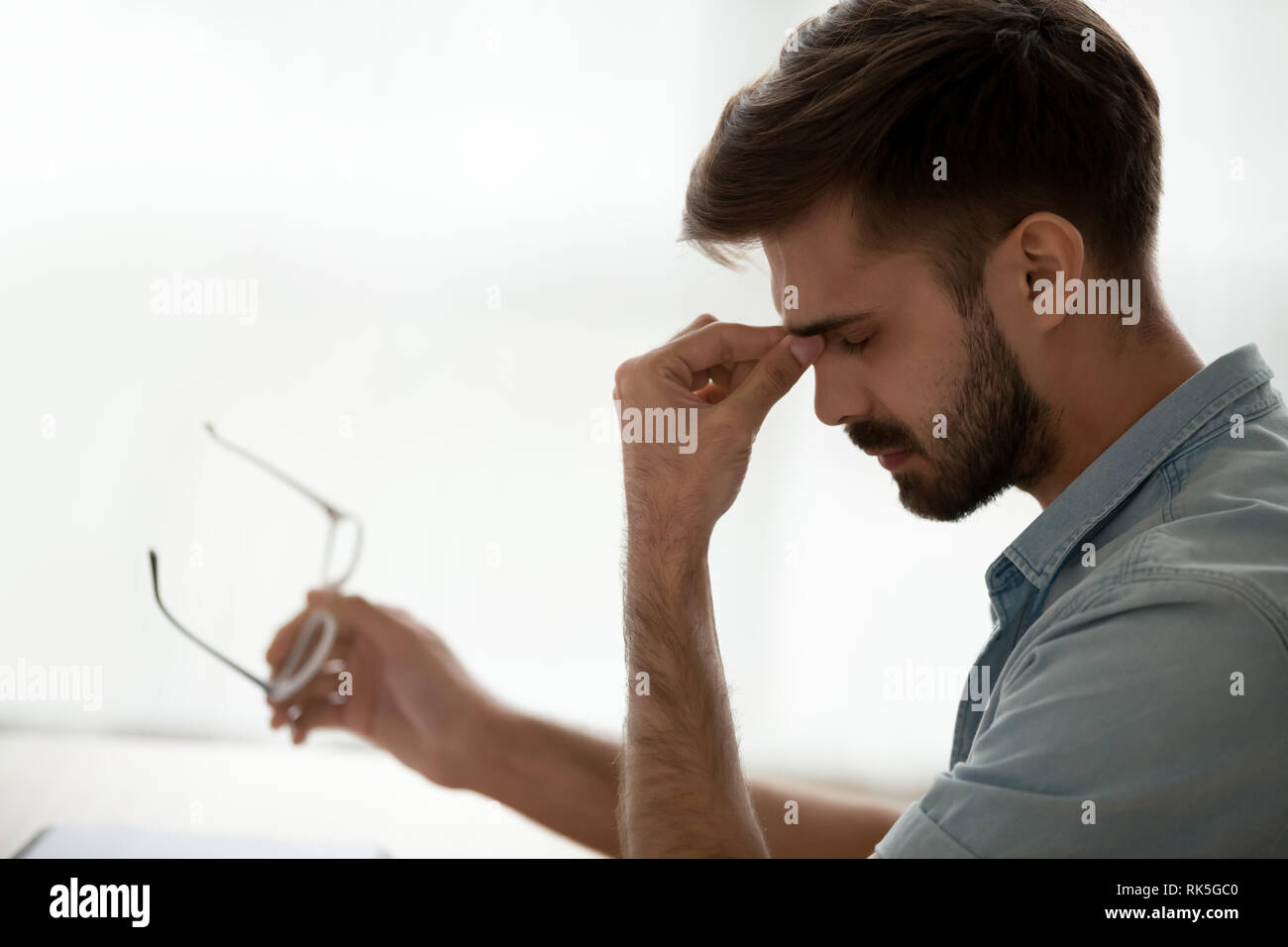 Tired stressed guy taking off glasses feeling eyestrain or headache Stock Photo