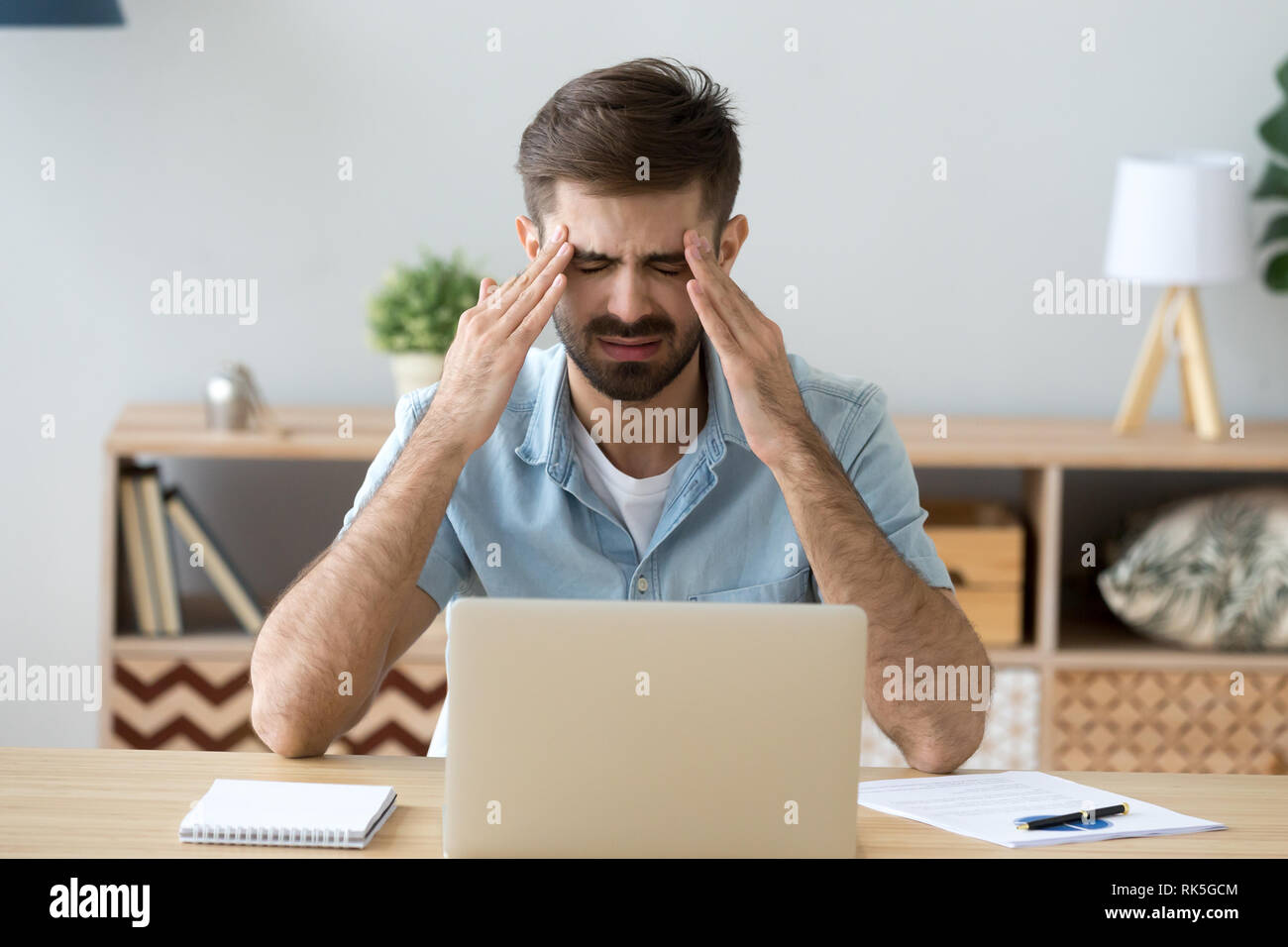 Stressed tired man having terrible headache after computer work Stock Photo