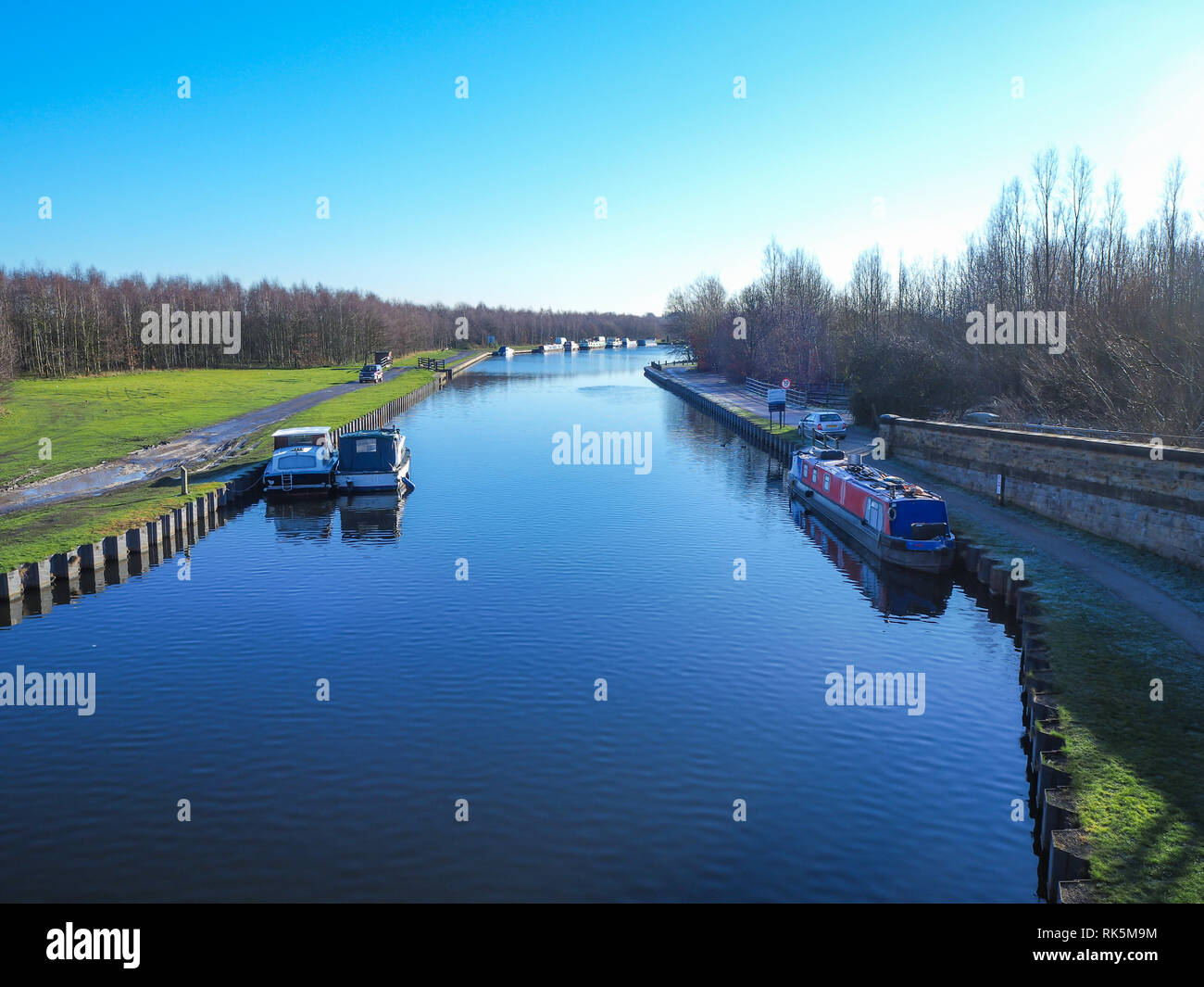 Boats on a section of the Aire and Calder Navigation in West Yorkshire, England, on a clear winter morning with a blue sky Stock Photo