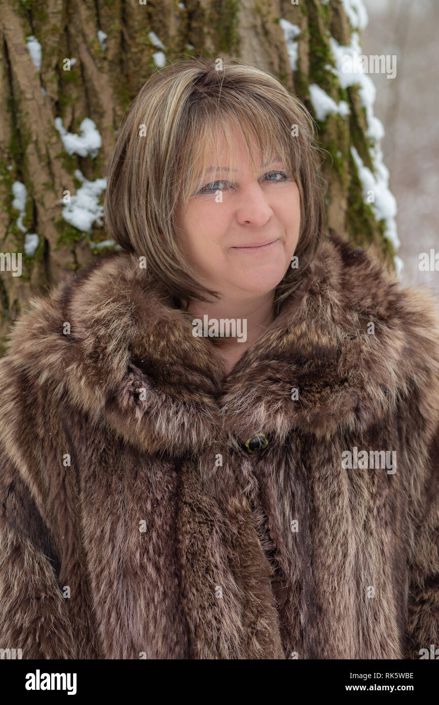 mature woman in fur coat outdoors looking at camera smiling Stock Photo