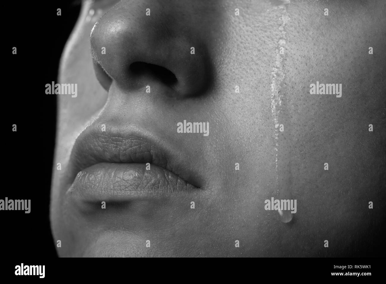 sad woman cries, shot a close up of female cheek with a tear drop, monochrome Stock Photo