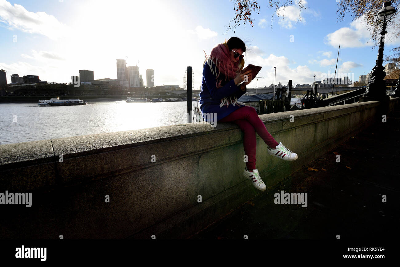 London, England, UK. Young woman on the Victoria Embankment looking at her mobile phone Stock Photo