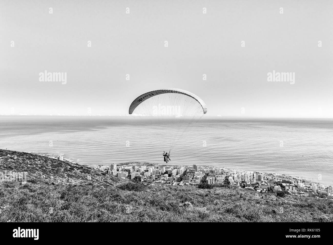 CAPE TOWN, SOUTH AFRICA, AUGUST 9, 2018: A tandem paraglider moments after launch from Signal Hill in Cape Town in the Western Cape Province. Sea Poin Stock Photo