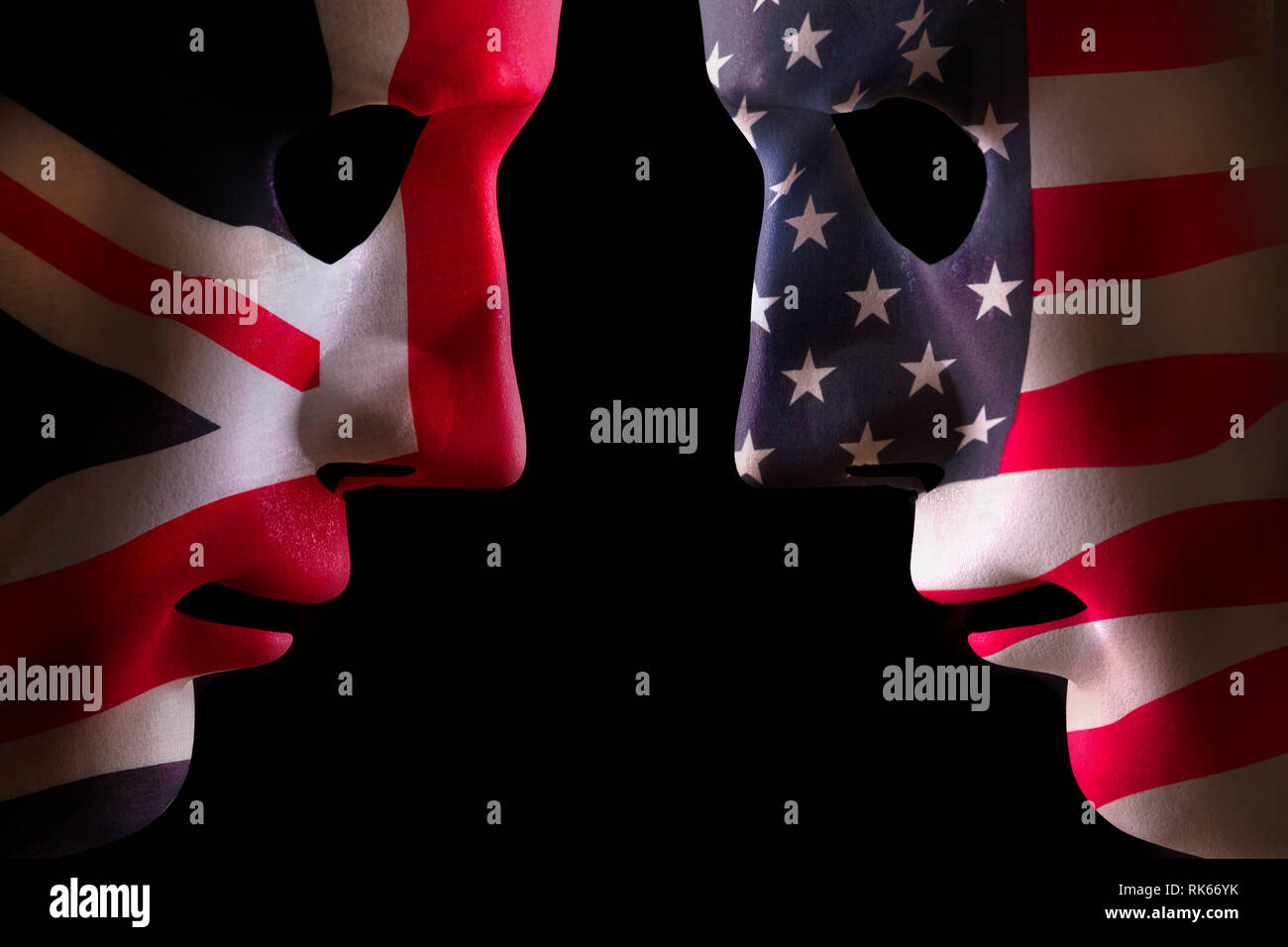 USA and GB face off head to head concept with human mask outlines covered in national flags symbols. Black background space for text Stock Photo