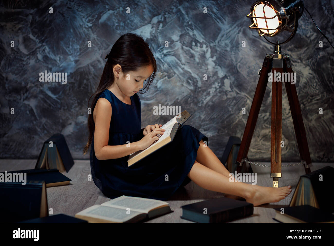 cute little girl sitting on the floor and reading a book in front of a ...