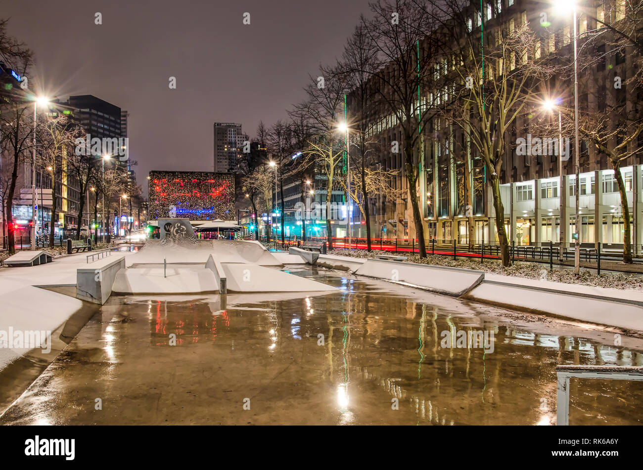 Rotterdam, The Netherlands, February 1, 2019: office buildings and street lights reflect on the wet concrete of the partly snow covered Westblaak skat Stock Photo