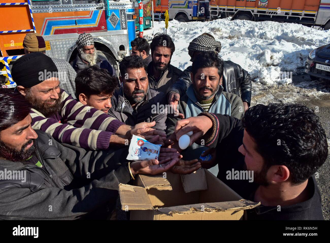 Kashmir, India. 9th Feb 2019. A local seen distributing packets of milk and eggs to the stranded truck drivers on a closed National Highway in Qazigund, about 85kms from Srinagar, Indian administered Kashmir.  The main National Highway that connects the valley with the rest of country remained closed on Saturday for the fourth consecutive day following an avalanche killing seven people including the three policemen, the two firefighters and the two prisoners. Credit: SOPA Images Limited/Alamy Live News Stock Photo