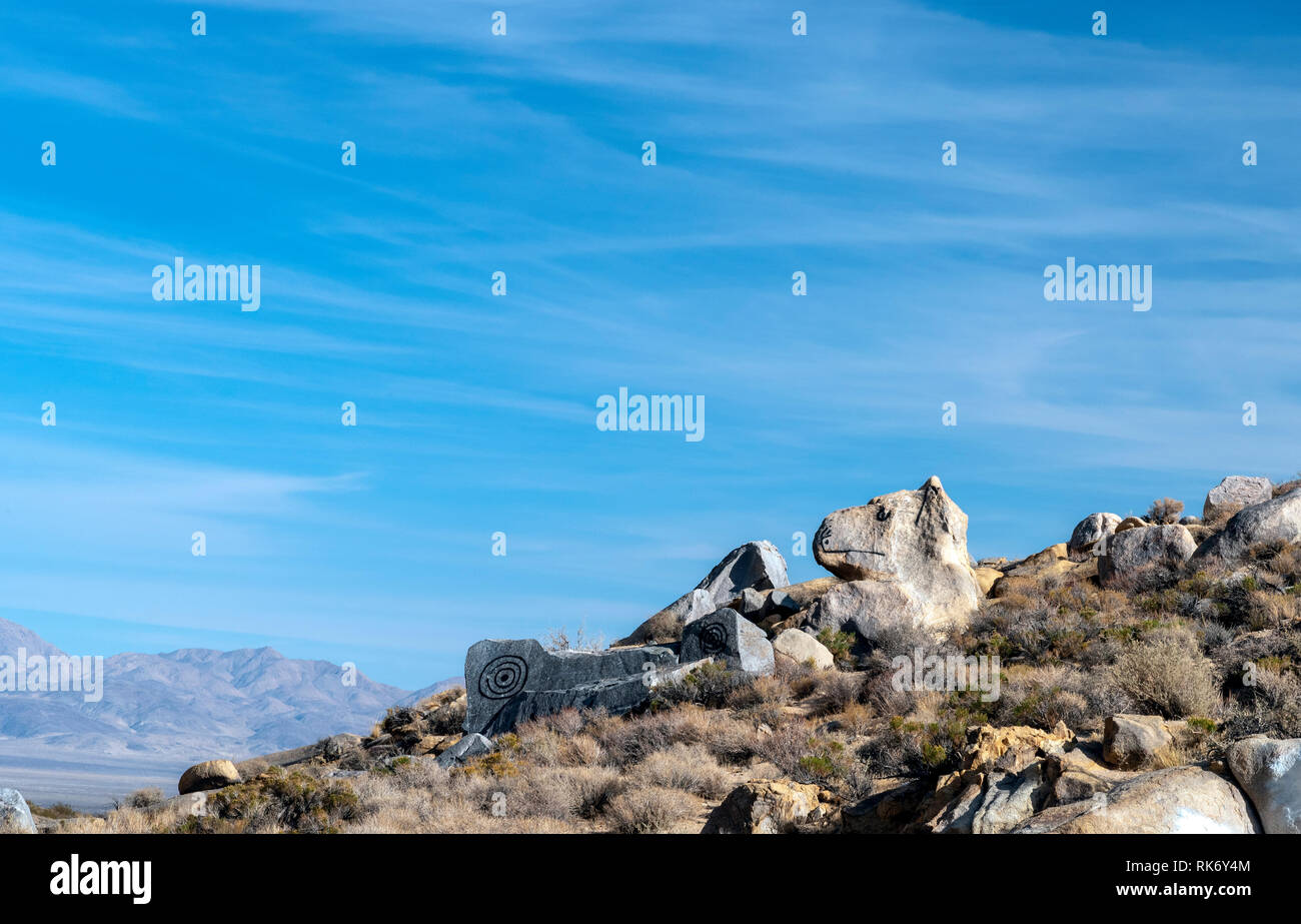 Dog shaped rock and modern Petroglyphs on desert hillside under bright blue sky. Stock Photo