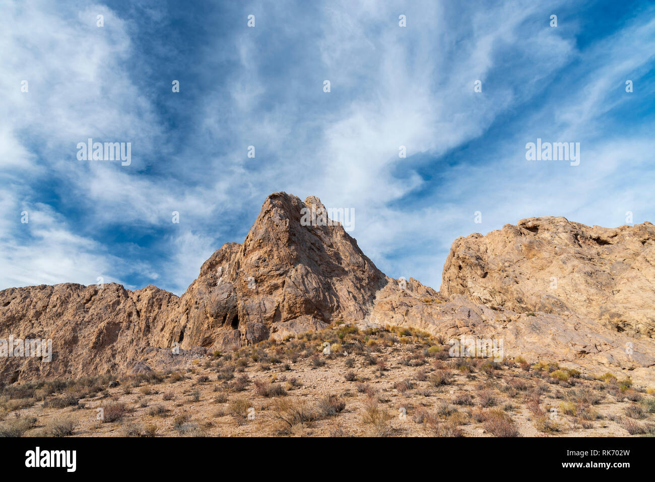 Desert rock formations under bright blue sky with wind blown clouds ...
