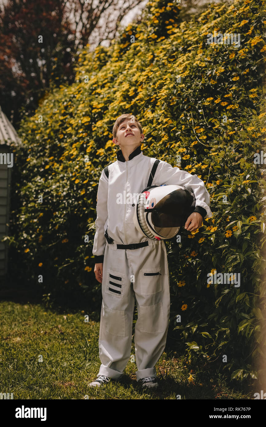 Kid playing in astronaut suit outdoors. Boy pretending to be an astronaut looking up. Stock Photo