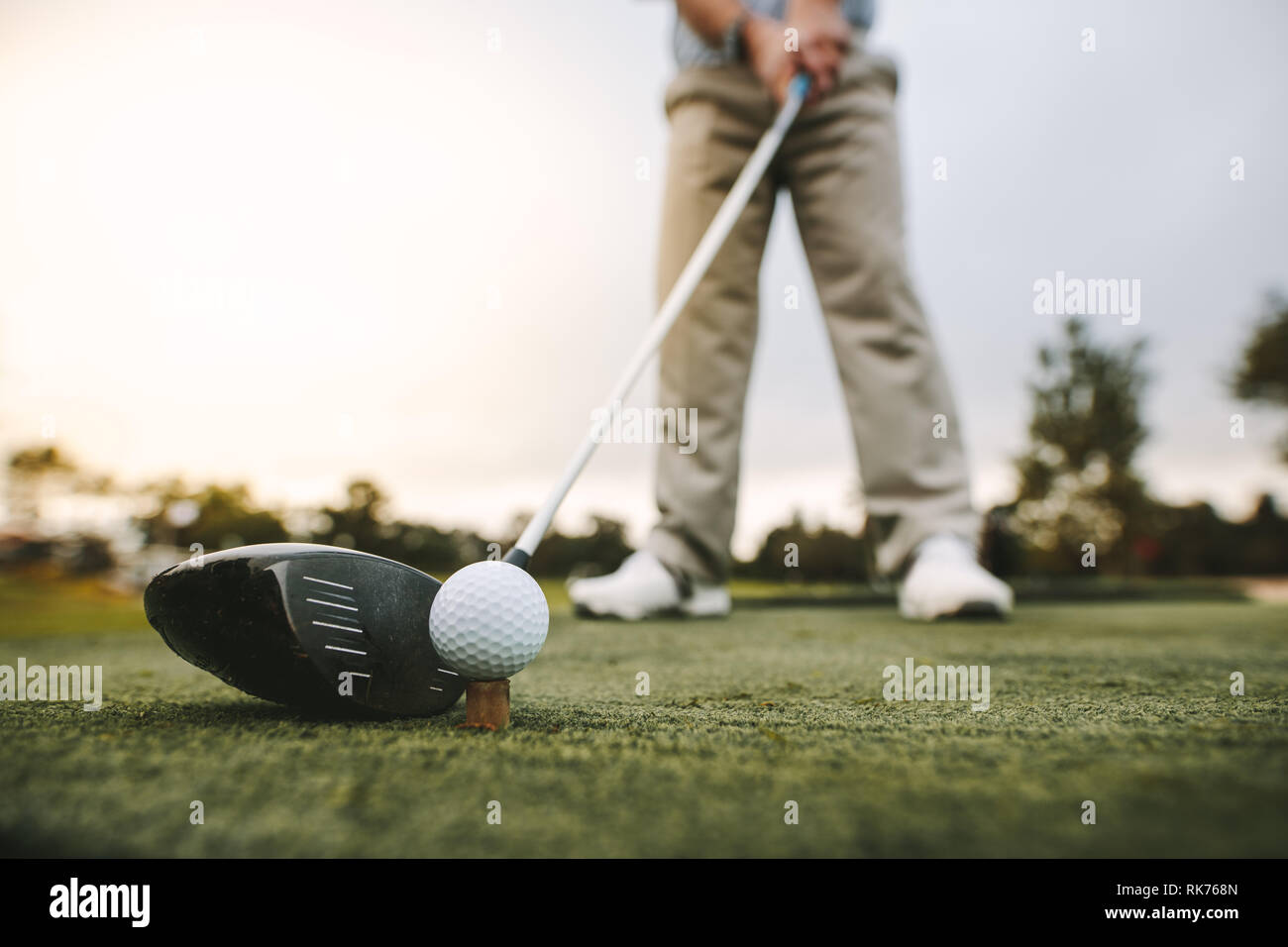Golf club and golf ball on tee at driving range. Focus on the head of the club and ball. Stock Photo