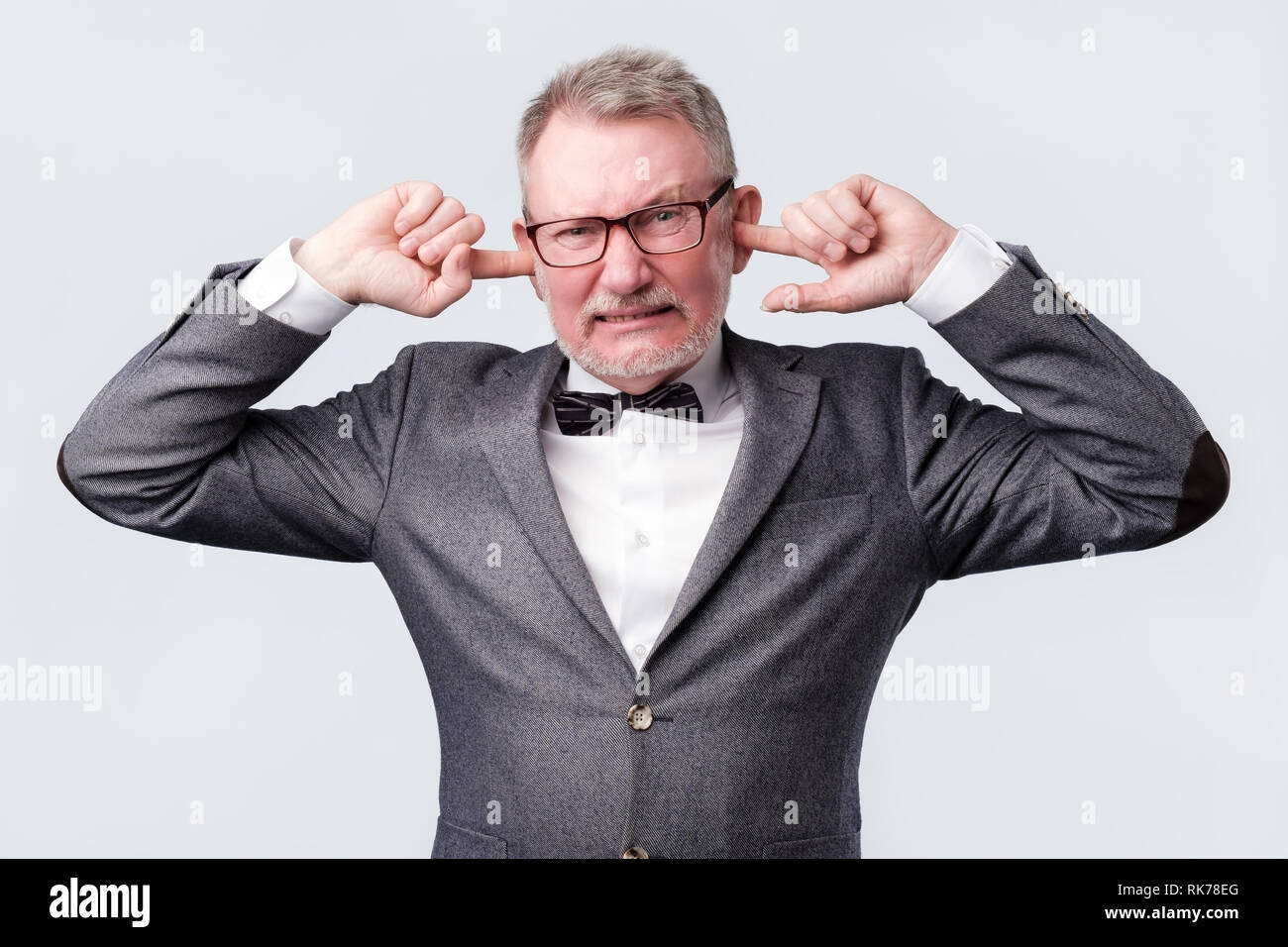 Senior man closing ears with fingers not wanting to hear something. Stock Photo