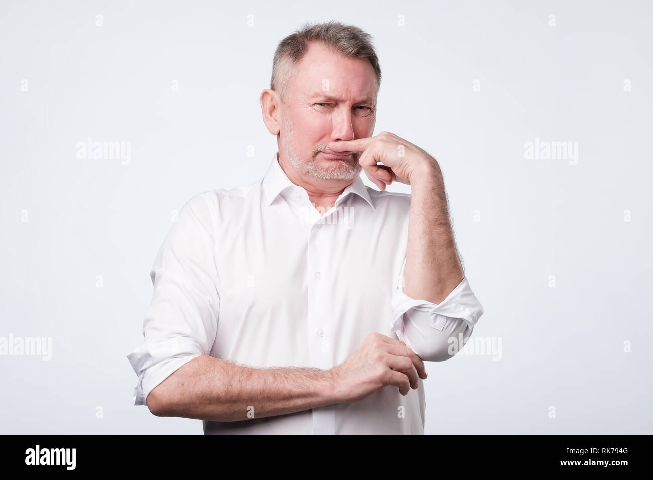 Man pinches nose with finger looks with disgust something stinks bad smell Stock Photo