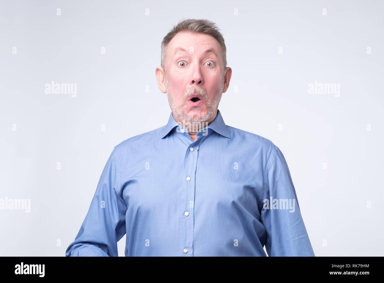 Senior man looks with astonishment into camera, being amazed with news. Stock Photo