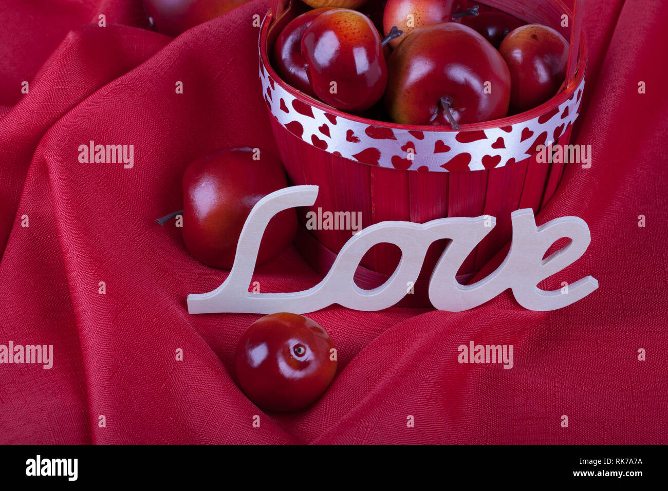 Valentine's day concept horizontal photo, apples in a red basket and the word love on the red background Stock Photo