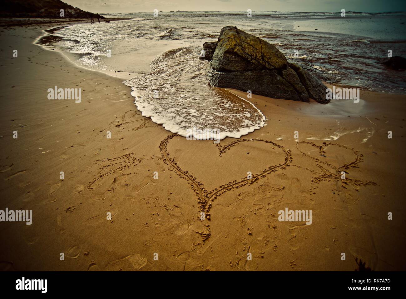 Love the beach, love the sea. A heart drawn in the sand of a beach with the tide coming in, Rhosneigr, Anglesey, North Wales, UK Stock Photo