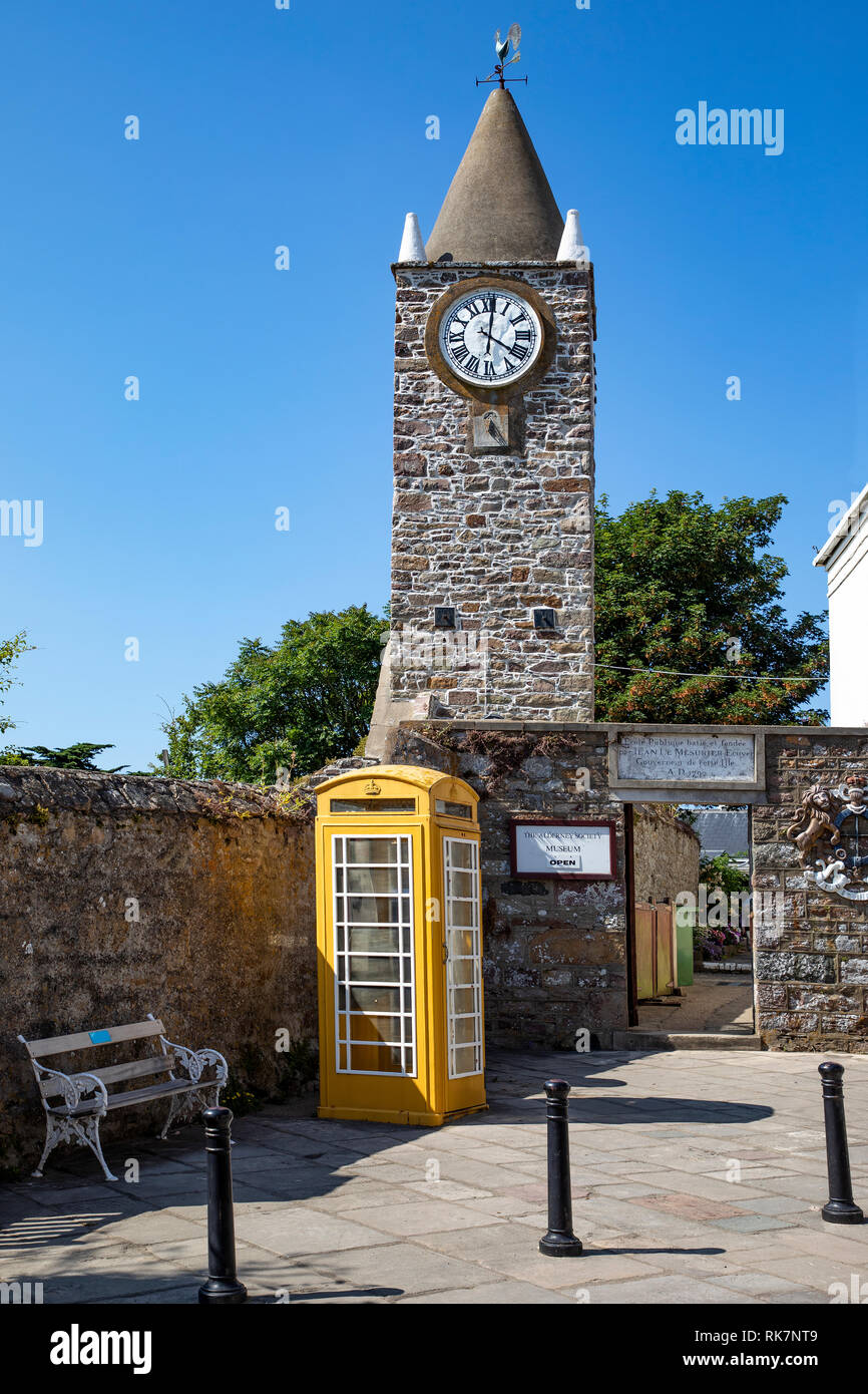 The Old Church Clock Tower and yellow telephone box at the Museum entrance, high street Alderney. Stock Photo