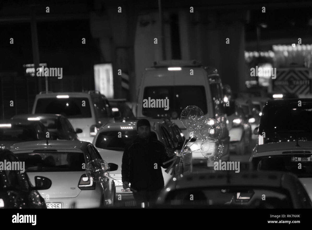 Vendor man sells led-light balloons at night at highway during a traffic jam in Altunizade, Asian side of Istanbul in black and white image. Stock Photo